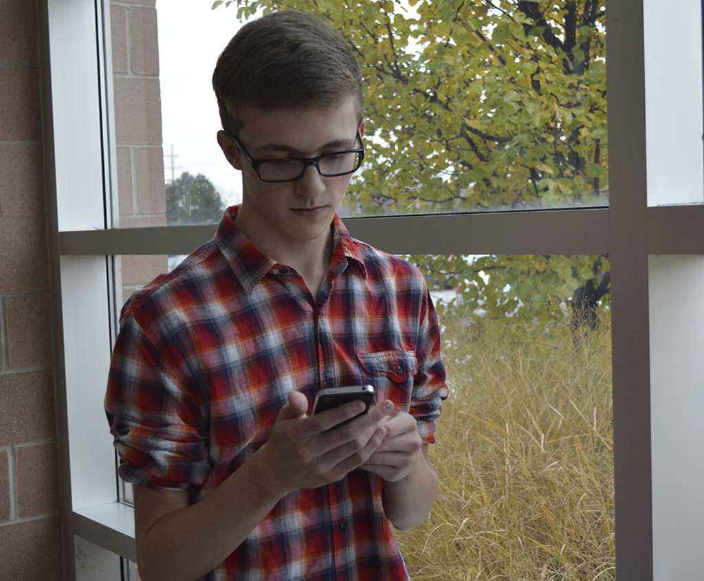 Senior Carter Scott dons a variation of the hipster look: thick glasses, plaid shirt with pulled-up sleeves, and iPhone. 