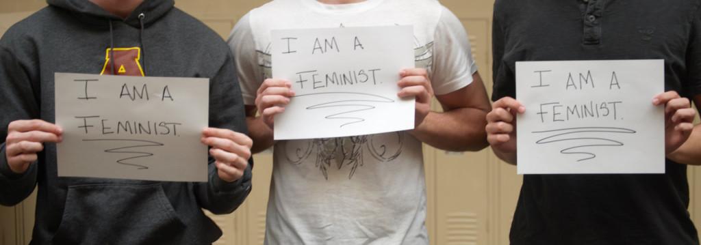 Male Adams students hold signs in support of feminism.