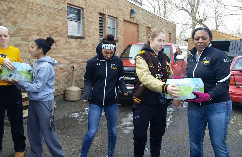 Players, [from left to right] Nicole Shaw, Nykka Brigoli, Taylor Smith, Hannah Simard, and Coach Shay Lewis in an assembly line to transport the water.