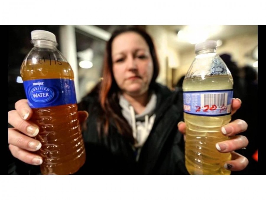 A Flint citizen holds up contaminated water from her tap.