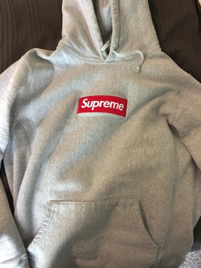 Light grey Supreme hoodie with red, stitched-in box logo costing approximately $300.
