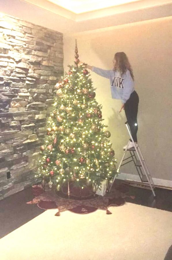 Riley Lilla taking her turn putting the star on top of the tree.