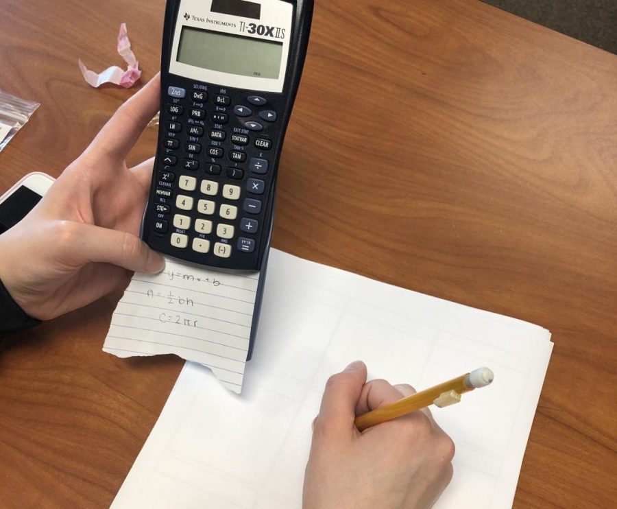 Student using a cheat sheet during a math quiz.