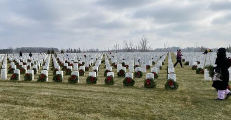 Volunteers help to lay down wreaths against gravestones at Great Lakes National Cemetery in Holly, Michigan. (Photo Credit: The Oakland Press)