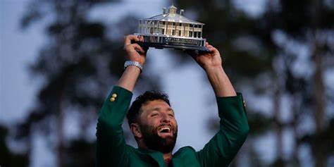 Masters winner John Rahm lifting his first Masters trophy and wearing the famous green jacket. (Photo Credit: newsfop.com)
